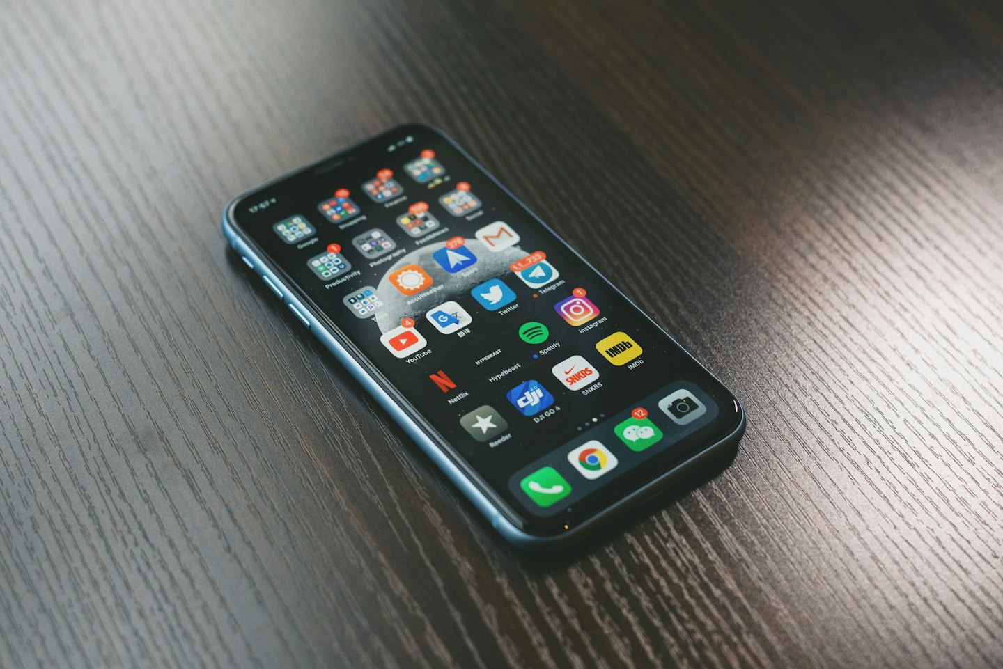 Nowoczesny smartfon leżący na ciemnym drewnianym stole.