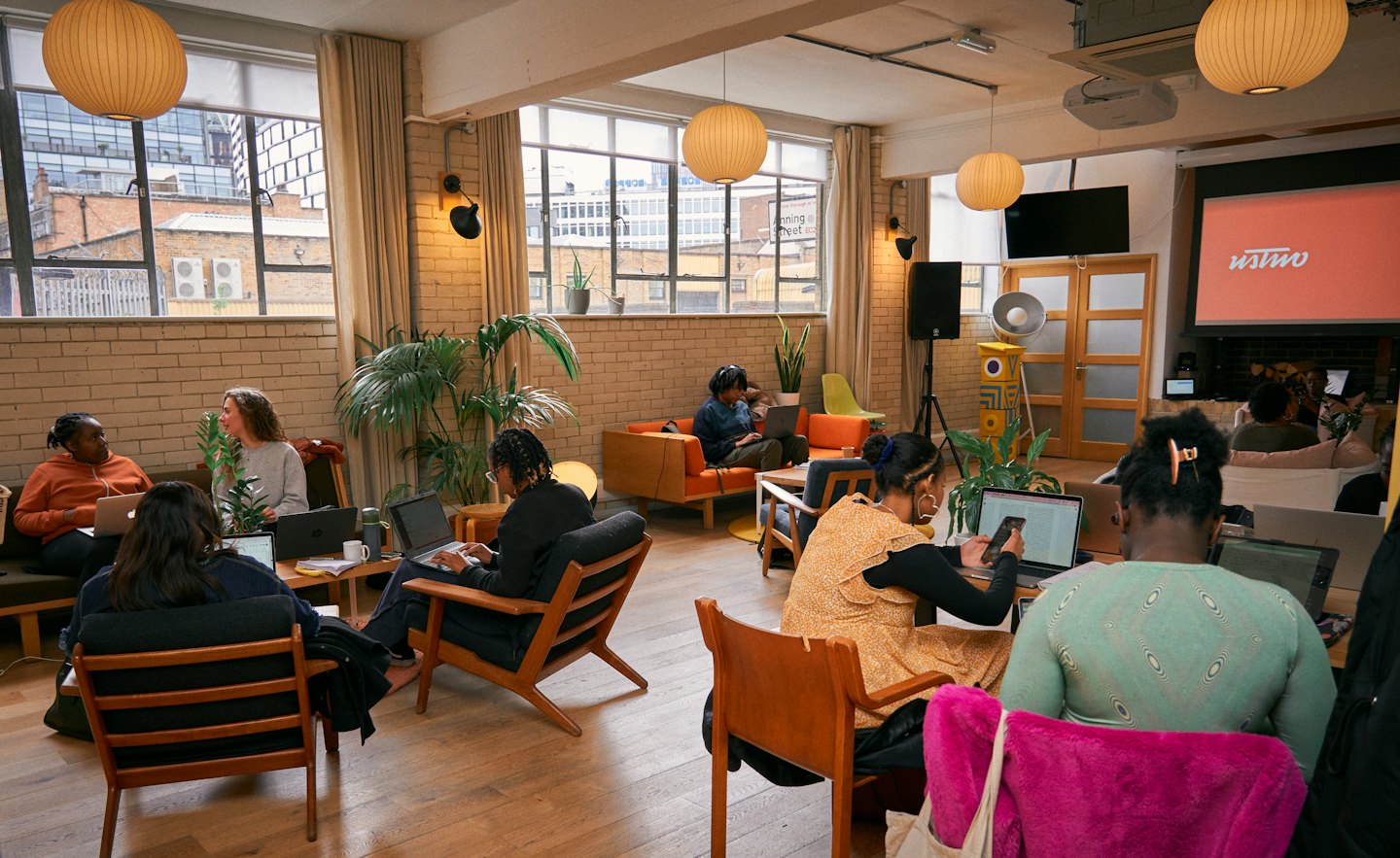 Ludzie pracujący razem na laptopach w otwartej przestrzeni coworkingowej.